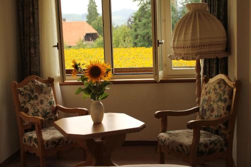 吕策尔弗吕奥伯多夫社区酒店的一间设有两把椅子的房间和一个带向日葵的花瓶