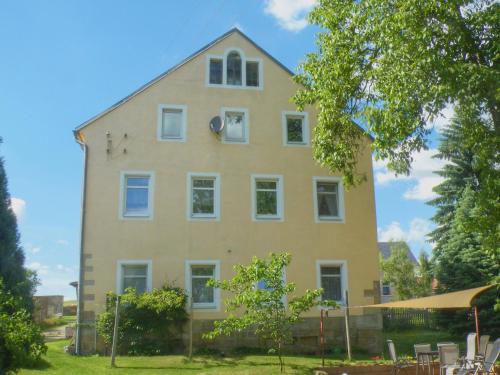 KirnitzschtalAm Lindenbaum的一间黄色的大房子,有白色的窗户和树