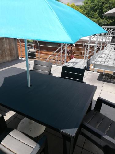 ZottegemNUVOLA Summer Spring的一张黑色桌子和椅子,配有蓝色雨伞