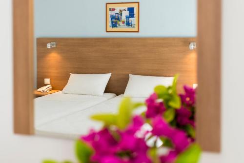 科林比亚HOTEL TINA FLORA的一间卧室配有一张带镜子和粉红色鲜花的床