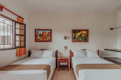梅里达Hotel Santa María Mérida的客房设有两张床、一张桌子和一扇窗户。
