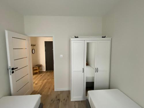 什切青Apartment Insat II的白色的客房设有两张床和一个衣柜。