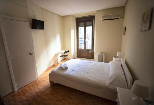 马德里Hostal Los Perales的卧室配有白色的床和窗户。