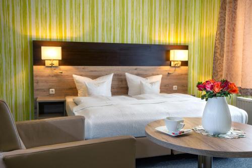 罗斯多夫Appart Hotel Roßdorf的一间卧室配有一张床和一张花瓶桌子