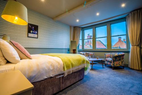 格拉斯顿伯里The Crown Hotel的一间卧室配有一张床、一把椅子和窗户。