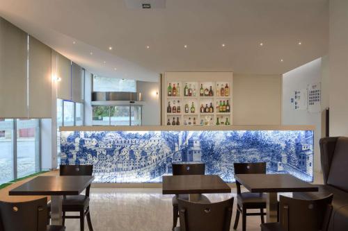 波尔图TRYP by Wyndham Porto Centro Hotel的用餐室配有桌椅和壁画