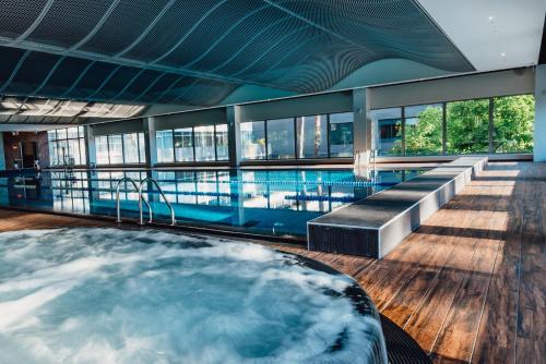 尤尔马拉斯玛拉里卢普SPA&会议酒店的一座带游泳池的建筑中间的热水浴池