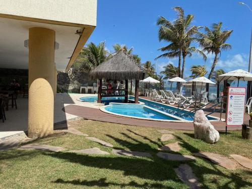 纳塔尔Elegance Hotel Natal Beira Mar的一个带椅子和遮阳伞的游泳池的度假酒店