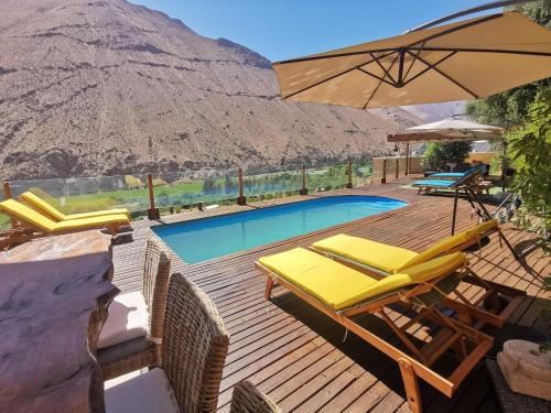 皮斯科艾齐Lodge Nueva Elqui的一个带椅子和遮阳伞的甲板和一个游泳池