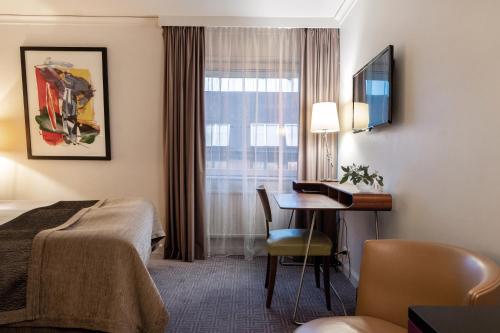 斯德哥尔摩斯德哥尔摩广场精英酒店的配有一张床、一张书桌和一扇窗户的酒店客房