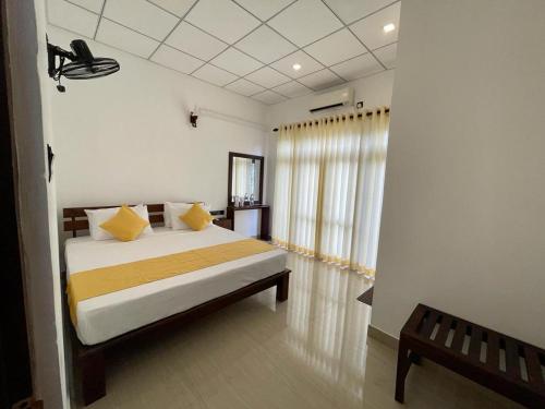 阿努拉德普勒Theon Resort的一间卧室配有一张带黄色枕头的床和一扇窗户