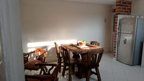 伊瓦格Apartamento Amoblado en Ibagué的厨房配有木桌、椅子和冰箱