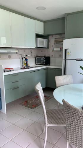 嘎林海斯港Marulhos Resort的厨房配有绿色橱柜和桌椅
