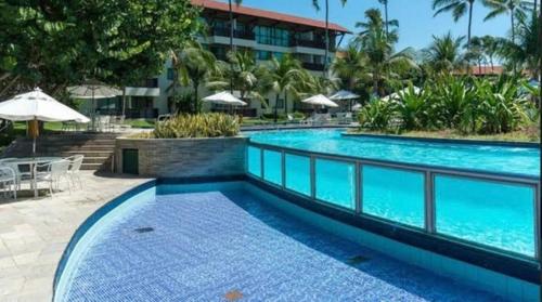 嘎林海斯港Marulhos Resort的度假村内的大型游泳池,配有桌子和遮阳伞
