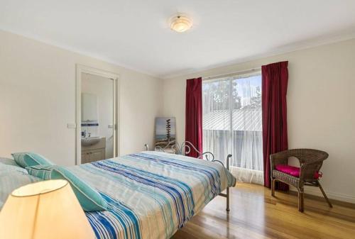 卡尔斯Phillip Island Time - Large home with self-contained apartment sleeps 11的卧室配有床、椅子和窗户。
