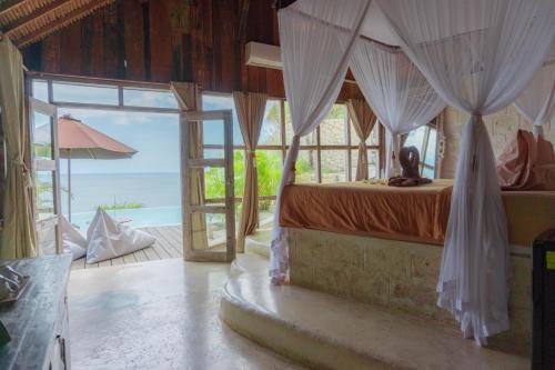 金巴兰La Joya Biu Biu Resort的一间卧室设有一张天蓬床,享有海景