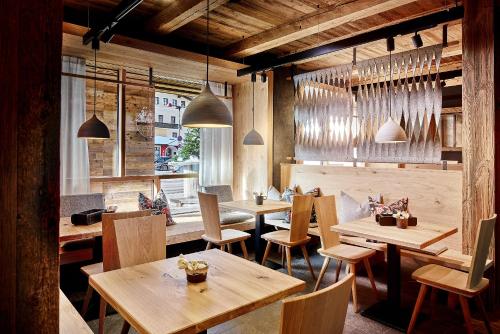 上陶恩佩内尔阿尔卑斯酒店的餐厅设有木桌、椅子和吊灯