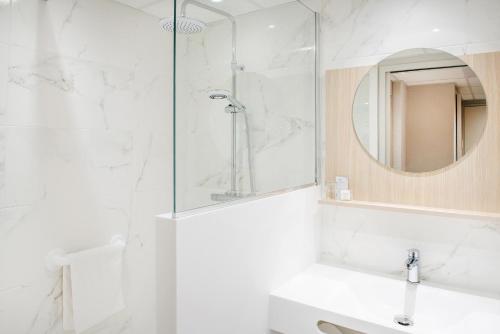 卢尔德圣索沃酒店的带淋浴、盥洗盆和镜子的浴室