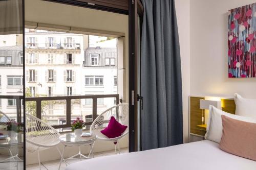 巴黎巴黎路易·勃朗站酒店的一间卧室配有一张床,阳台配有桌椅