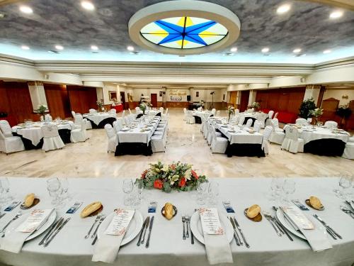 雷阿尔城圣锡西利亚酒店的一个带白色桌子和餐具的大型宴会厅