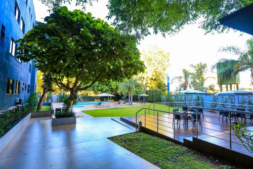 伊瓜苏伊瓜苏快捷酒店的一座公园,公园里有树和桌子,还有一座建筑