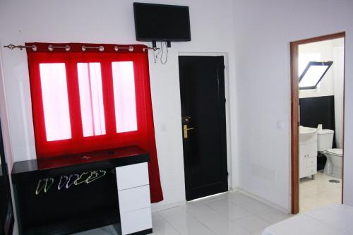 埃斯帕戈斯Académico do Sal的一间设有红色窗户的客房,墙上配有电视