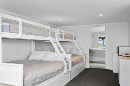 陶波Acacia Bay的一间白色卧室,内配两张双层床