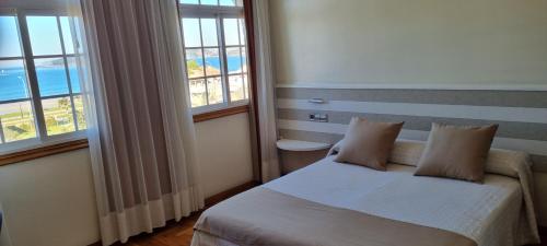 美洲海滩Hotel Miramar Playa America Nigran的一间卧室配有带2个枕头的床和2个窗户。
