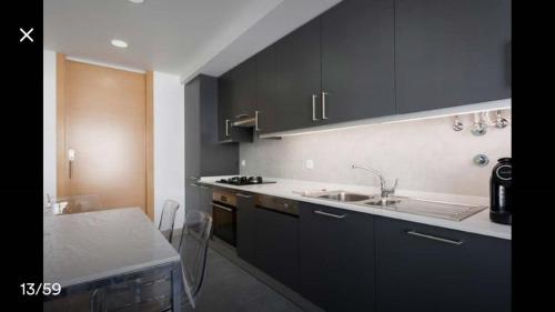 萨卡文Modern Apartment for Family and Group of Friends的厨房配有黑色橱柜、水槽和桌子