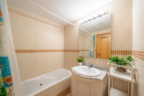 马尼尔瓦Apartamento con vistas al mar en Manilva Playa的一间带浴缸、水槽和镜子的浴室