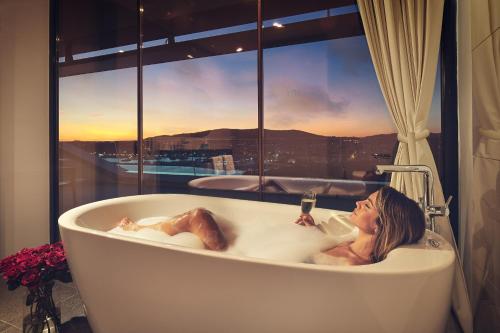 沃迪切Hotel Olympia Sky的躺在窗前浴缸中的女人