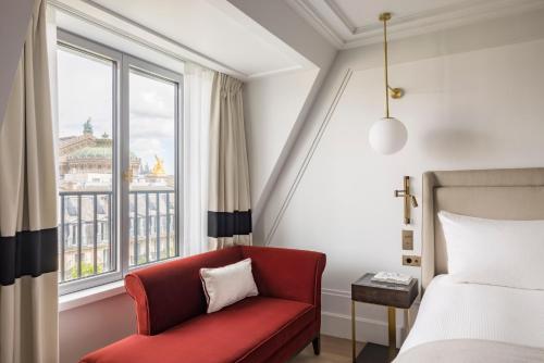 巴黎Kimpton - St Honoré Paris, an IHG Hotel的一间卧室配有红色椅子、一张床和一个窗户