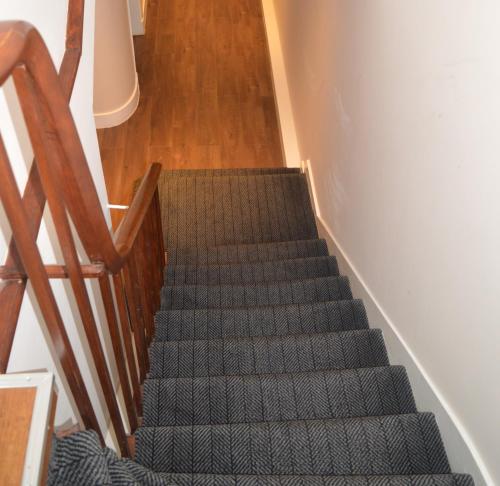阿伯丁Jewel Guest House的铺有绿色地毯的楼梯和木楼梯间