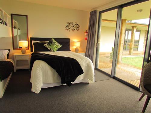 WaiauThe Bunkhouse的一间卧室设有一张床和一个滑动玻璃门