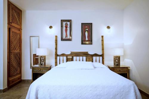 尼格瑞尔Beach House Condos, Negril的卧室配有白色的床和2个床头柜