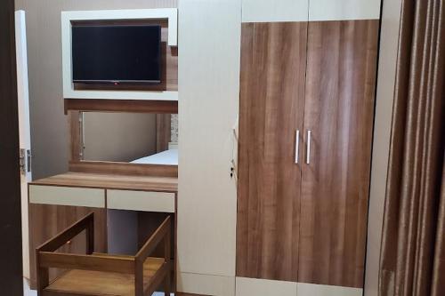 KudusRedDoorz near Simpang Tujuh Kudus的客房设有带电视和椅子的橱柜。