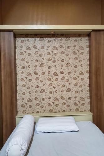 KudusRedDoorz near Simpang Tujuh Kudus的一张带床头板的床铺,上面有图案的墙壁