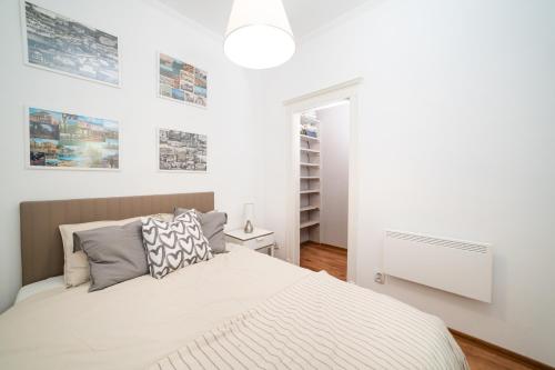 布达佩斯Cozy apartment in Budapest near Gellért Hill的一间白色的卧室,配有一张床和墙上的一些照片