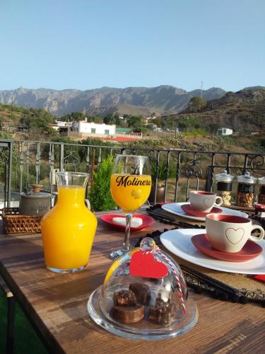 圣卢西亚Romantic Casa Rural La Molinera的一张木桌,上面放着一杯橙汁和一盘食物