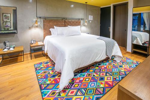 帕斯托Hotel V1501的一间卧室配有一张大床和色彩缤纷的地毯。