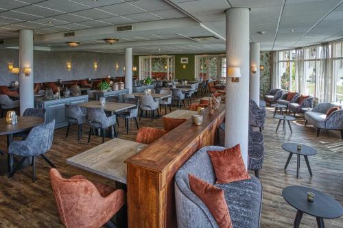 德科赫Landgoed Hotel Tatenhove Texel的一间带桌椅的餐厅和一间酒吧