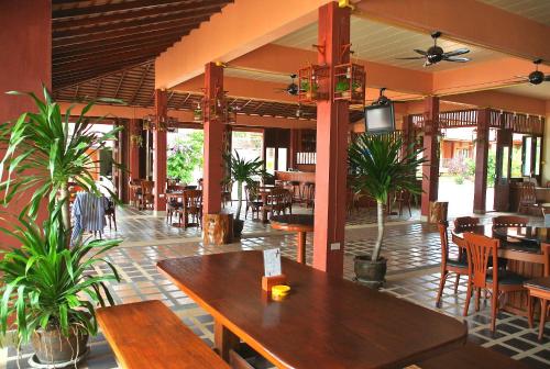 曾蒙海滩PS Thana Resort的餐厅设有木桌和椅子,种有植物