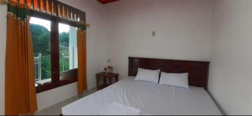 图克图克Toba Boi的一间卧室配有一张带白色床单的床和一扇窗户。