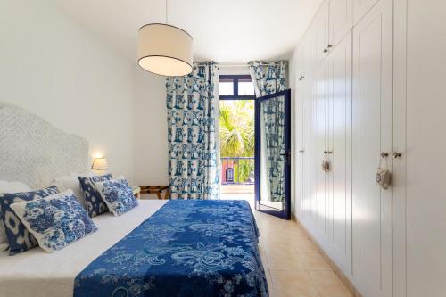 梅罗那瑞斯Meloneras Sunset的卧室配有蓝色和白色的床和窗户。
