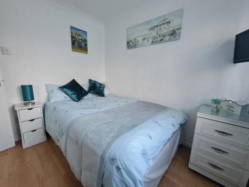 桑当Isle of Wight Chalet的一间白色卧室,配有床和床头柜