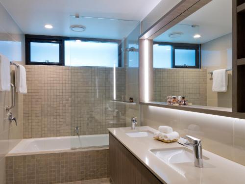 布里斯班格伦套房酒店的一间带水槽、浴缸和镜子的浴室