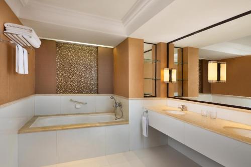 日惹Sheraton Mustika Yogyakarta Resort and Spa的浴室设有2个水槽、浴缸和镜子