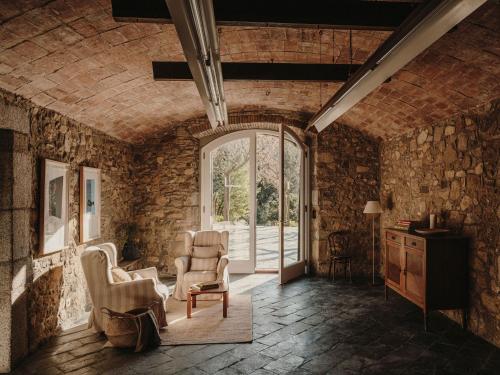 Llinars del VallèsParatgea的客厅设有石墙、椅子和窗户