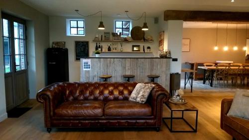 Velzeke-RuddershoveMuntershof的客厅里设有棕色皮沙发,还有酒吧