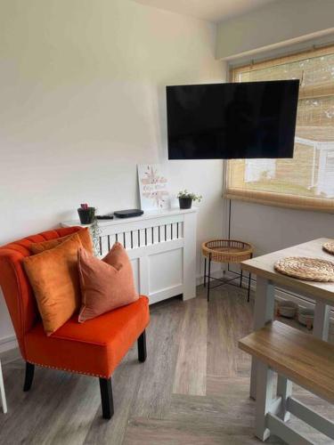 BeltonRuby’s Retreat的客厅配有橙色椅子和平面电视